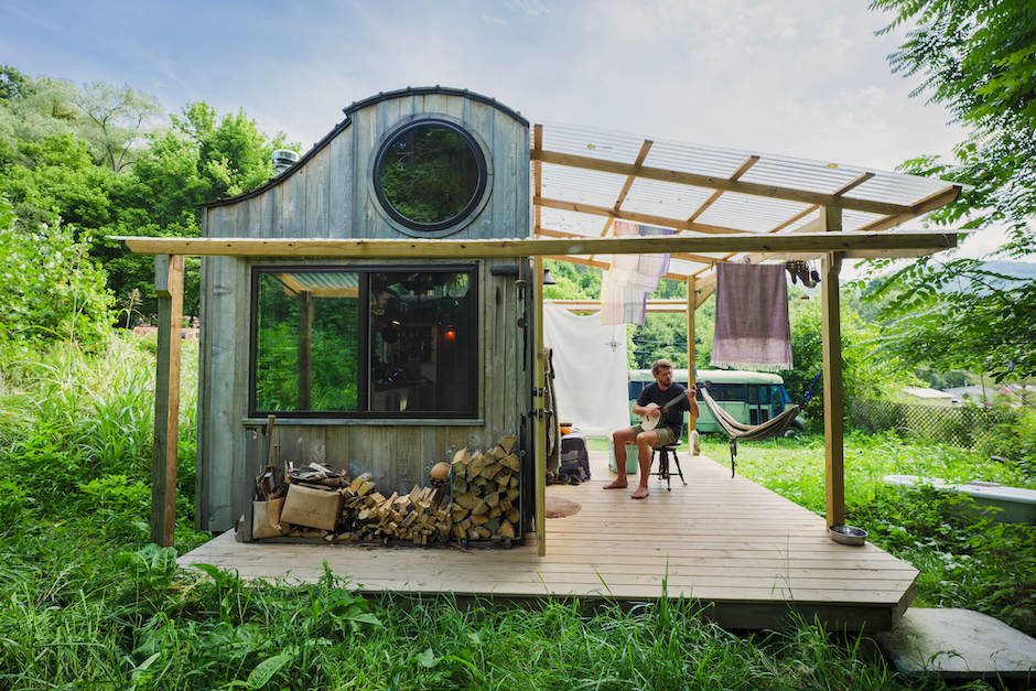 Man playing banjo outside tiny house