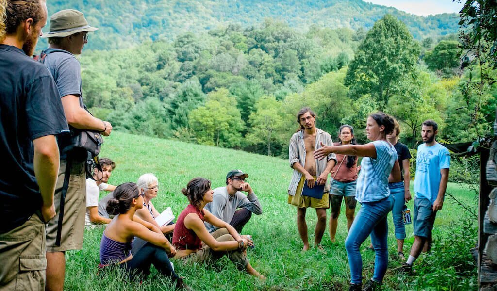 Instructor teaches students outdoors near mountain during permaculture design course