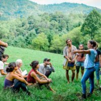 Instructor teaches students outdoors near mountain during permaculture design course