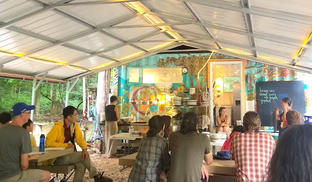 Mealtime at Earthaven. Students gather underneath tent