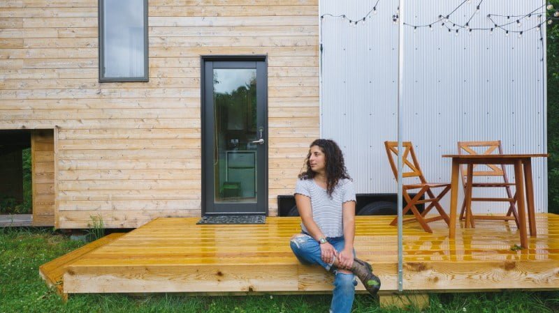 woman sitting on front deck of tiny house