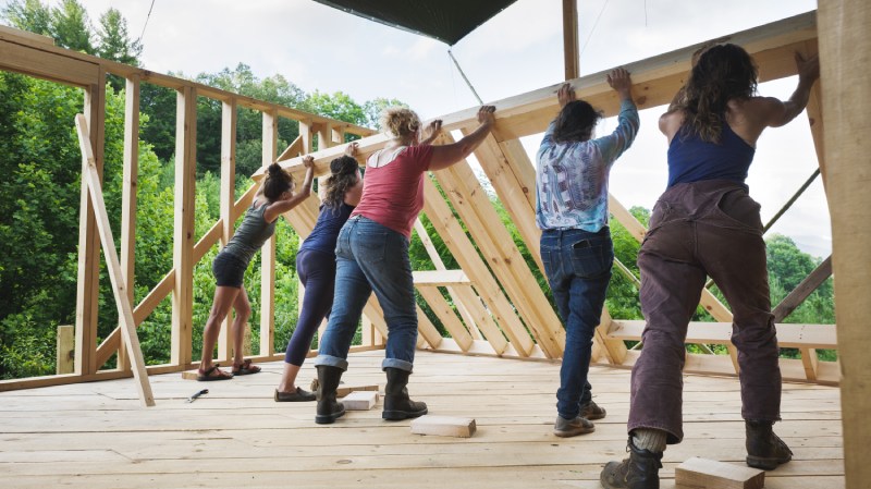 five women raising a wall in a tiny house workshop