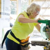 Woman uses table saw during tiny house workshop