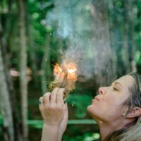 Student blowing on lighting tinder bundle during survival skills class
