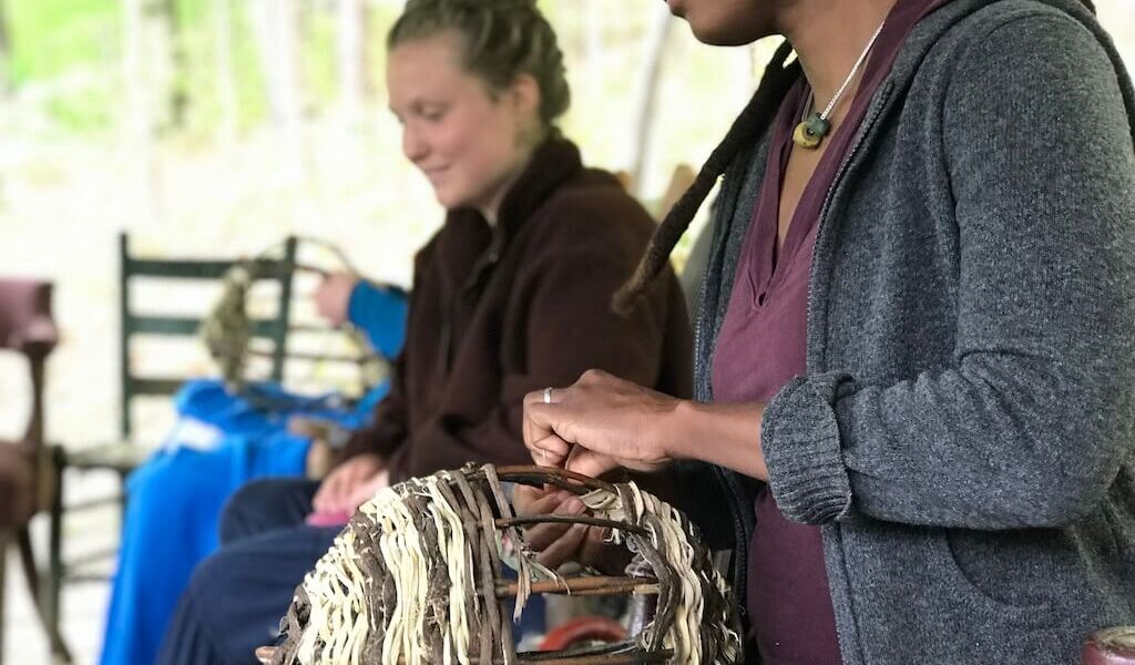 Two women weave baskets during women's rewilding weekend