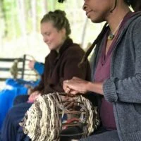Two women weave baskets during women's rewilding weekend