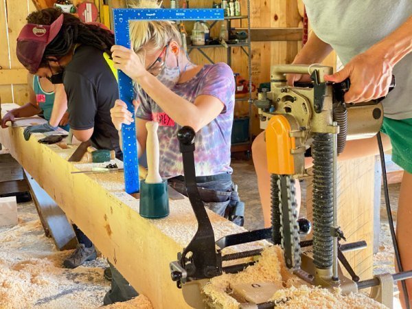 students in a timber framing class working together with mallets, mortiser, framing square, chisels