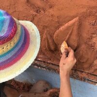 Person in bucket hat using natural building techniques to save money on tiny house