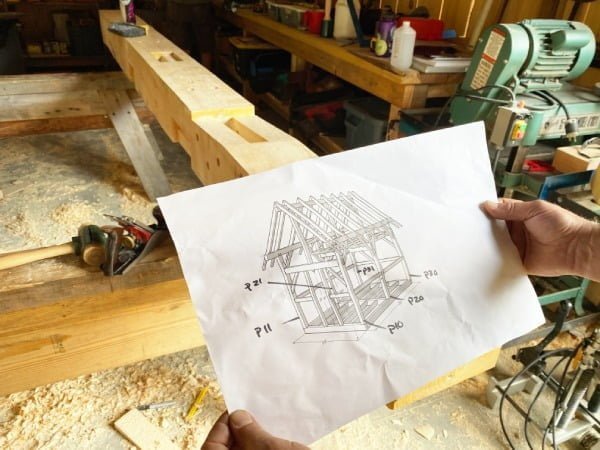 hands holding up a paper with an image of plans for a timber framed cabin
