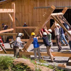 Students safely raising a timber framed building during class