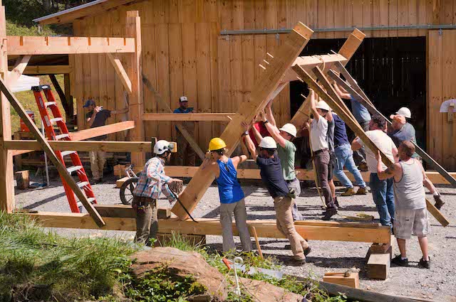 Students safely raising a timber framed building during class