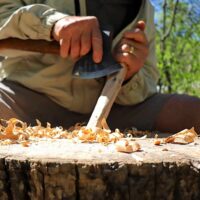 Student uses ax to carve during survival skills class