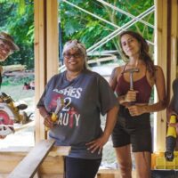 Four women stand holding tools during tiny house class