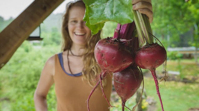 Woman holding up big beautiful beets from her garden