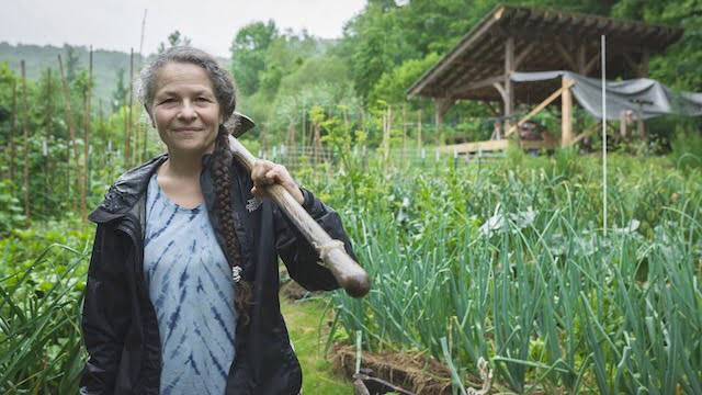 Woman with a hoe over her shoulder in the garden