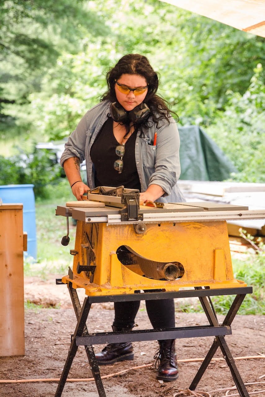 Woman using a table saw tool for building a tiny house
