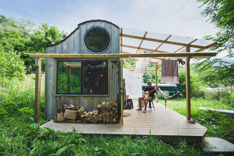 Man plays banjo outside tiny house