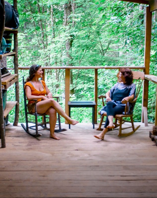 Two people on rocking chairs on the porch of a tiny house