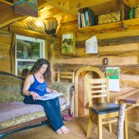 woman reading in her log cabin tiny house