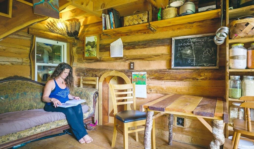 Woman reads book while living in a tiny house
