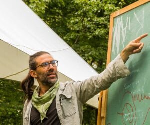Zev Friedman, main instructor for the PDC course, points at a blackboard in an outdoor classroom