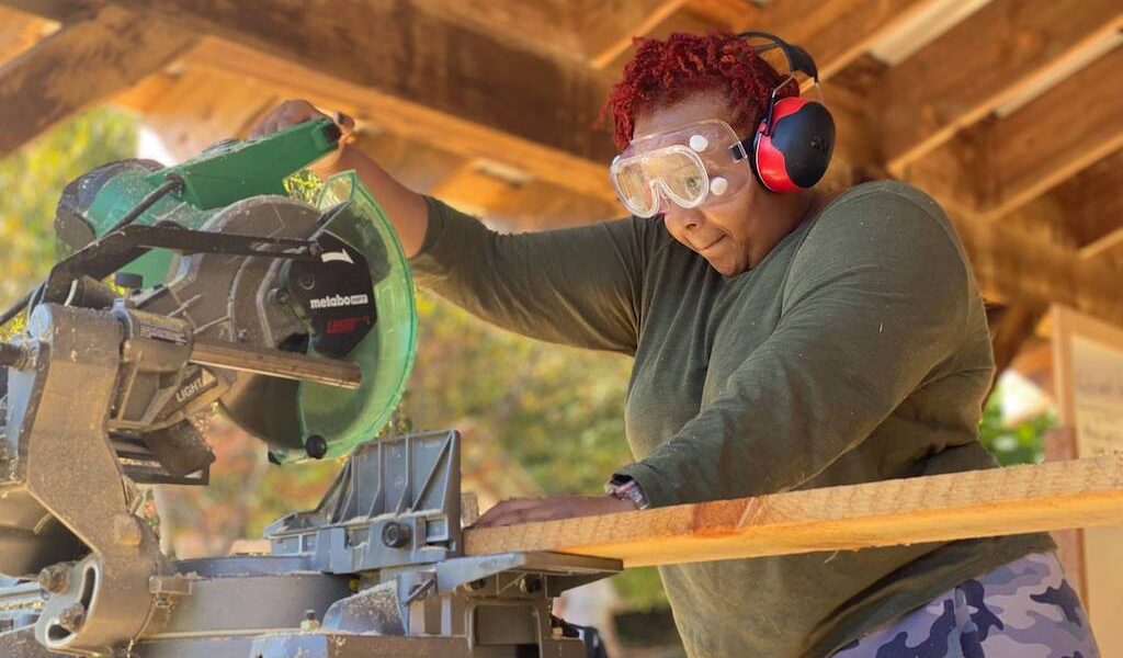 Woman uses saw during all genders carpentry class