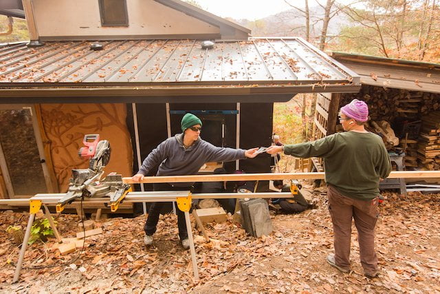 Two students pass tool during building apprenticeship.