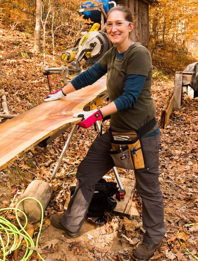Woman using a saw to cut rough lumber during all genders carpentry class