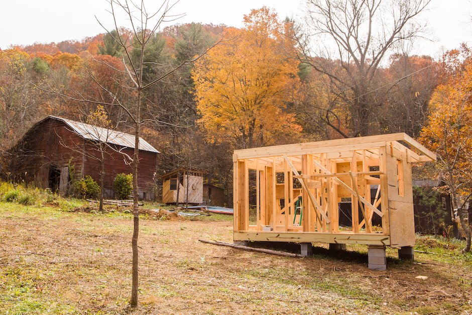 Wild Abundance Paint Fork Campus. Photo features partially built tiny house in foreground and barn in background. 