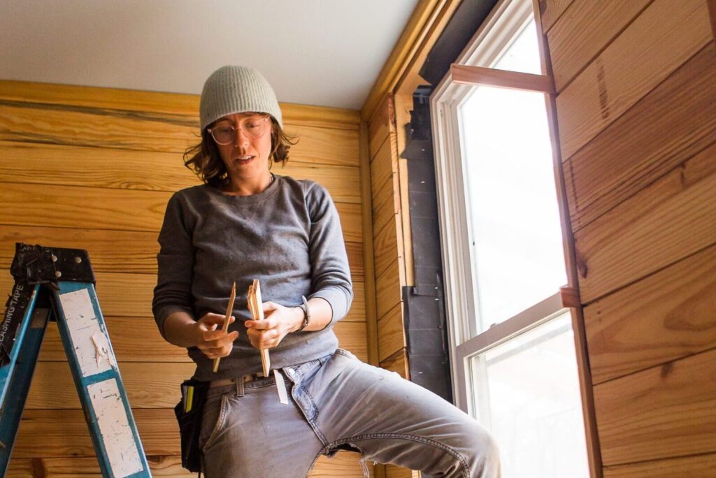 woman standing between ladder and a window using sustainable building materials