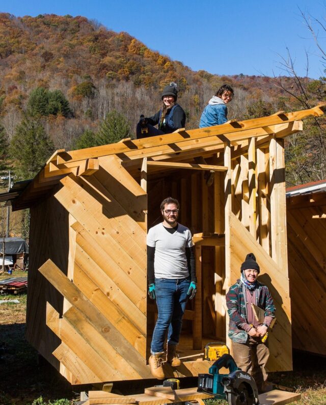 Group picture of students in the four month hands-on carpentry program in front of a structure they are building