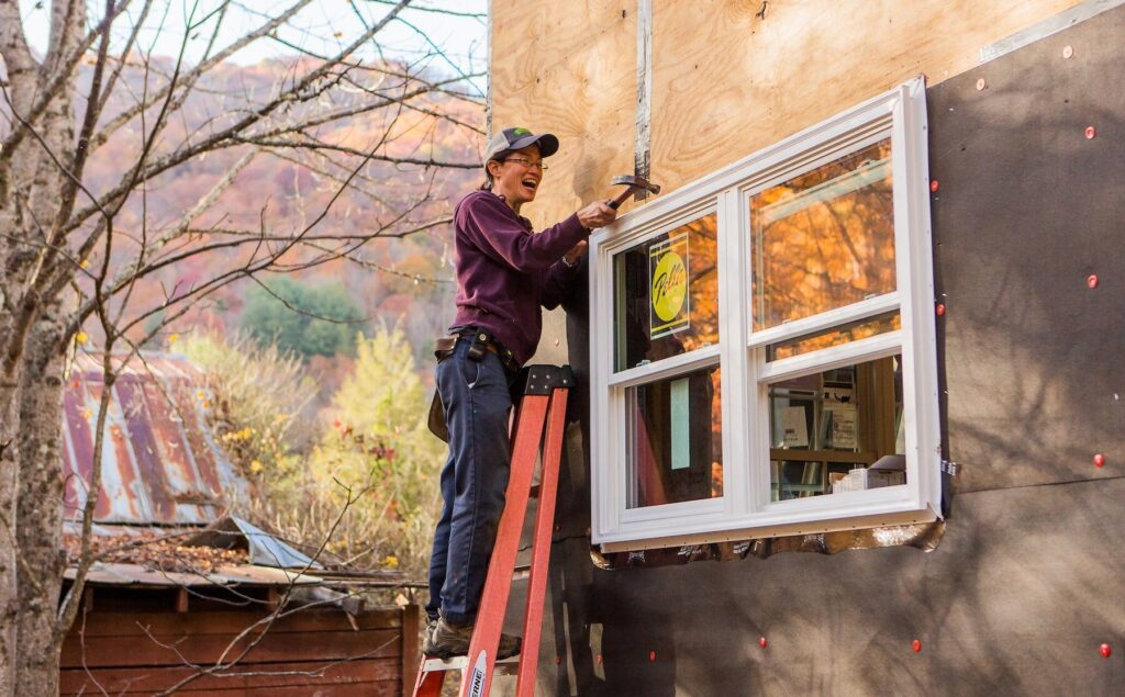 A female student completes a window installation during a tiny house building workshop