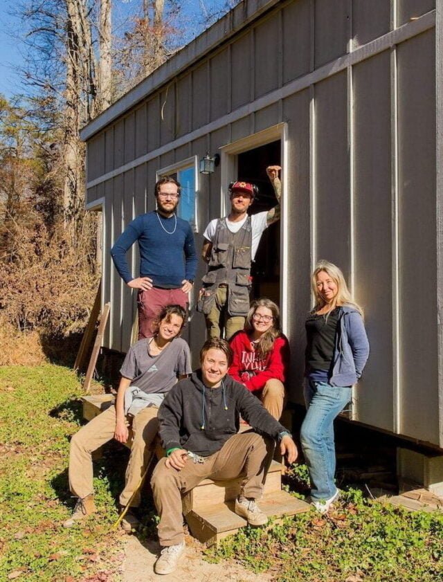 group photo of students in a four month buliding program with a structure they worked on