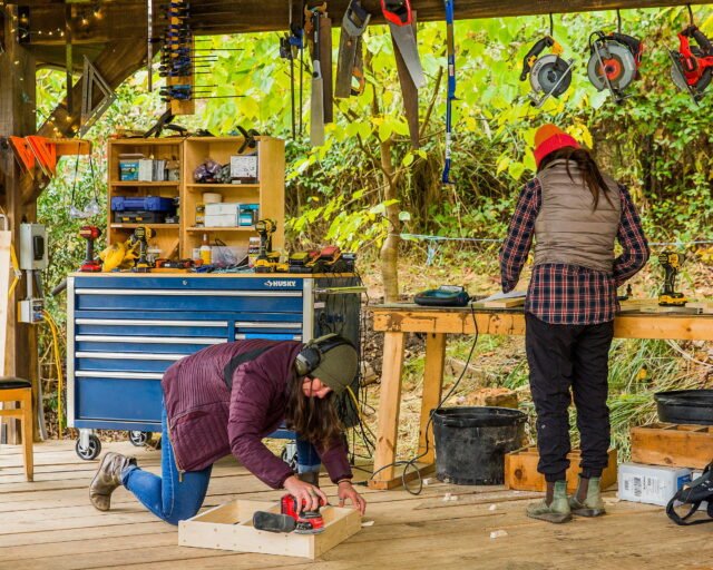 Two women students enjoying the open air wood shop classroom as they build their carpentry projects on the final day of the wild abundance workshop