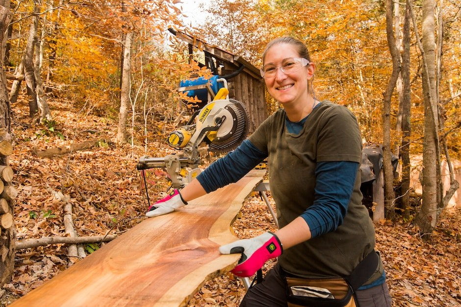A female student smiles with a piece of live edge exterior siding boards in a carpentry and building program