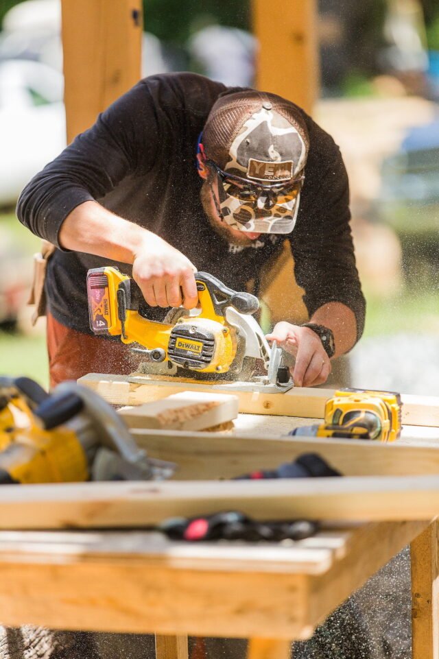 A male student makes cuts with a circular saw during a carpentry camp at Wild Abundance