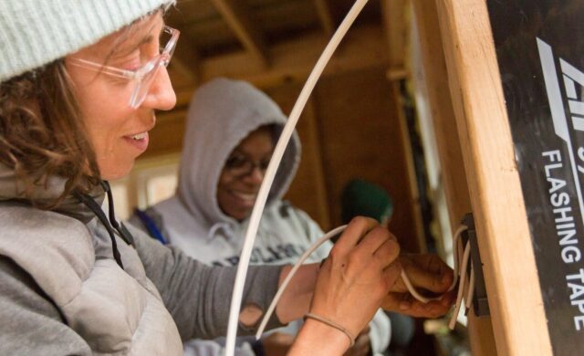 Two students work with electrical during a hands-on building program