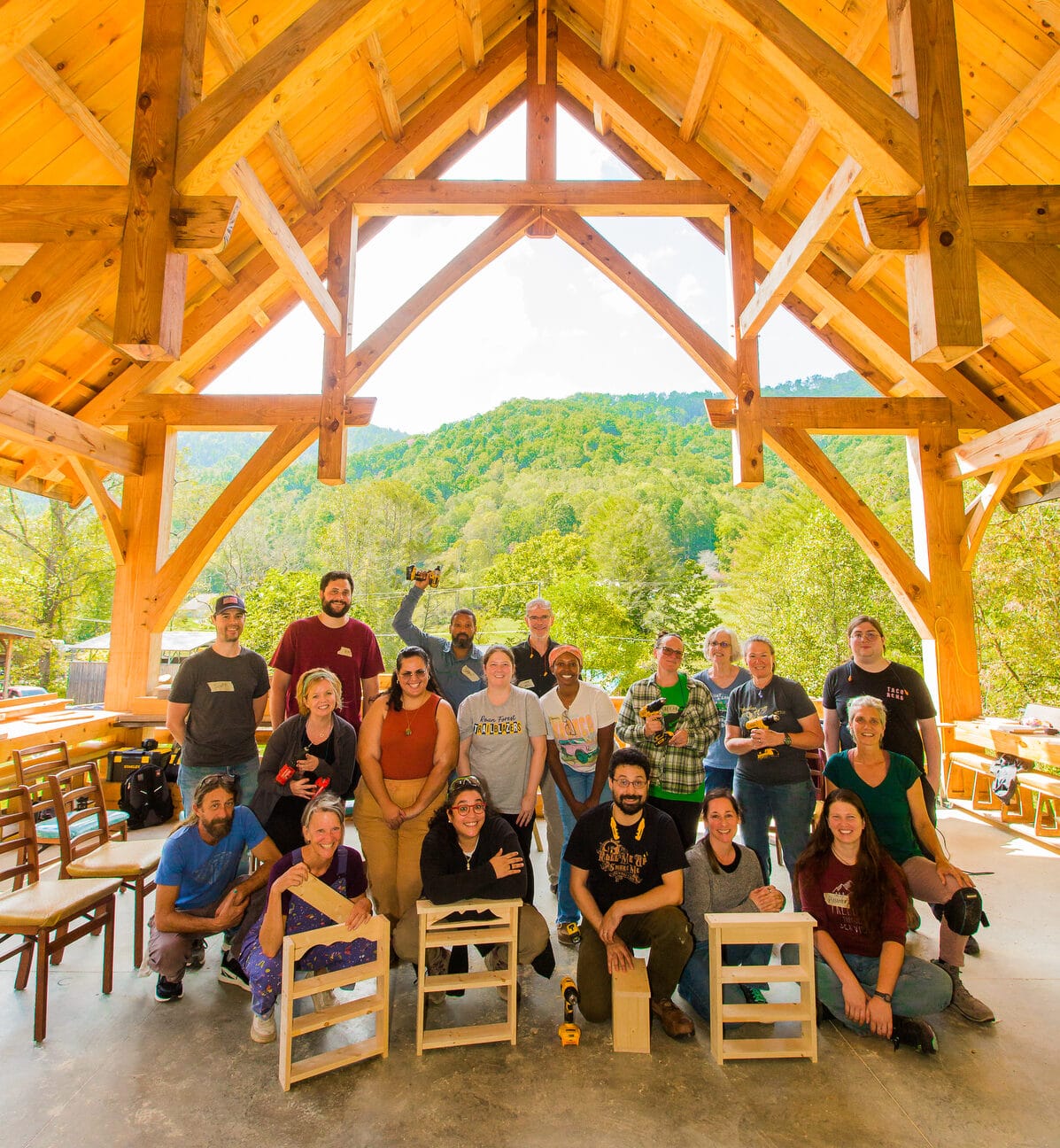 ABC 2025-1200-Current-219 Students in a carpentry class smile with their final projects for a group picture on the 4th and final day of the workshop