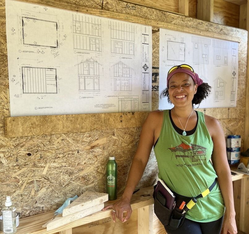 Woman poses in front of plans during tiny house workshop
