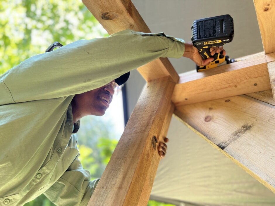 A woman screws in a rafter on a shed building project at a women's advanced carpentry class at Wild Abundance