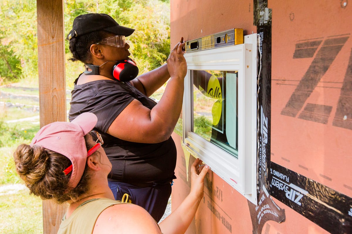 THIPW-1200-Current-79 A woman gets hands-on experience installing a window during the last day of a 10 day Tiny House Workshop at Wild Abundance in North Carolina