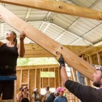students lift rafter boards into place during a tiny house building workshop