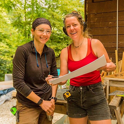 A female instructor and a student look at building plans for a structure they are constructing with a women's advanced carpentry class at Wild Abundance in North Carolina