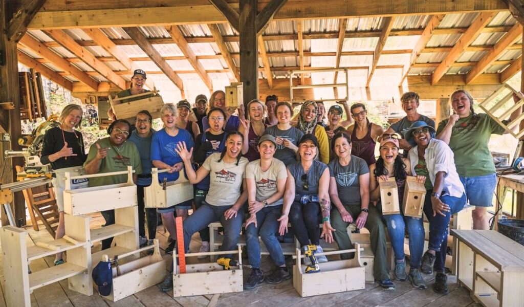 Students in a women's basic carpentry class smile with their woodworking projects