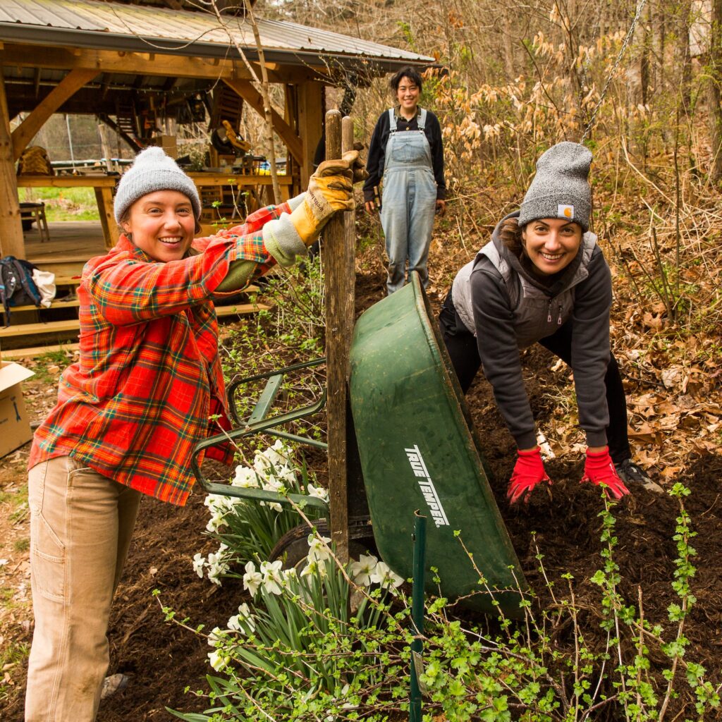 Apprentices smile up from mulching tasks in the wild abundance perennial garden beds
