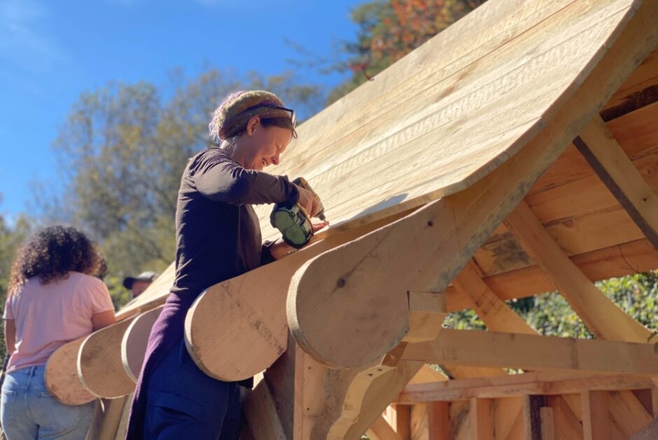 Woman working on a the roof of a building with her advanced carpentry class