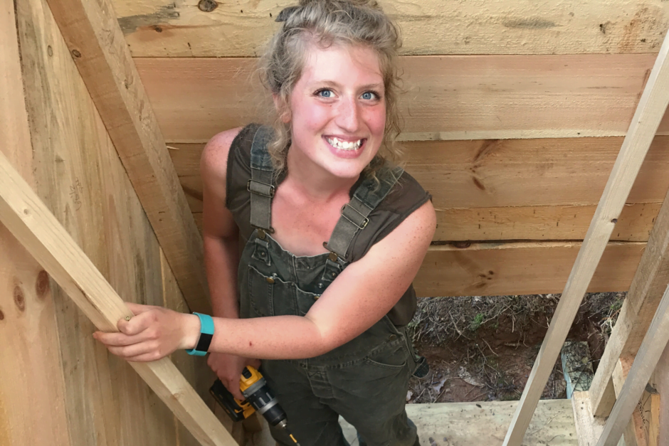 Young woman smiles as she works on walls during an advanced women's carpentry class