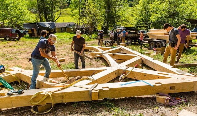 Students in a Timber Framing class are preparing the first bent to be lifted into place, building the teaching pavilion at the Paint Fork carpentry campus for Wild Abundance