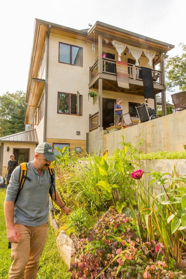 A PDC students inspects a permaculture guild in the terraced gardens outside of an off-grid sustainable home built at Earthaven Ecovillage