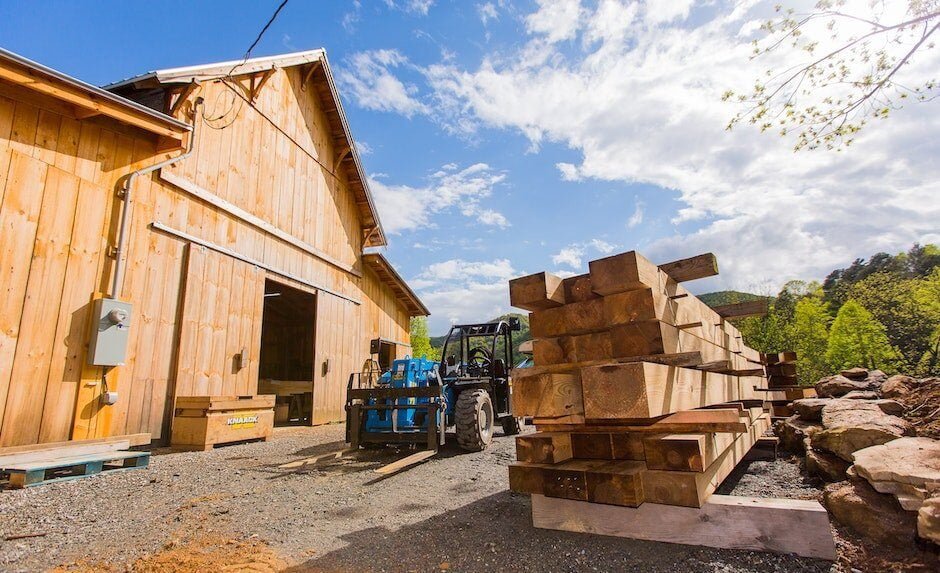 The exterior of Ivy Creek Timber Framing Workshop with a pile of stacked beams 